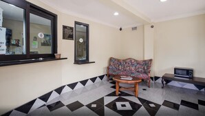 A reception area with a check-in counter, a sofa, a small table, and a television. - Hollywood Inn (Houston)