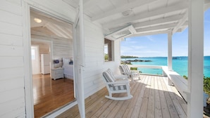 Une terrasse en bois avec des fauteuils à bascule donnant sur une plage.