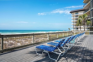 Eine Terrasse mit blauen Liegestühlen mit Blick auf Strand und Meer.