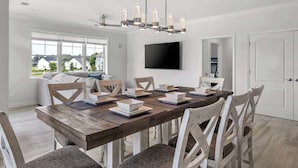 Un'area pranzo moderna con un tavolo in legno, sedie bianche e un lampadario.