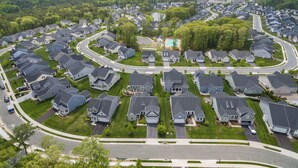 Vista aerea di una zona residenziale con case disposte a cerchio attorno a un'area verde centrale con una piscina.
