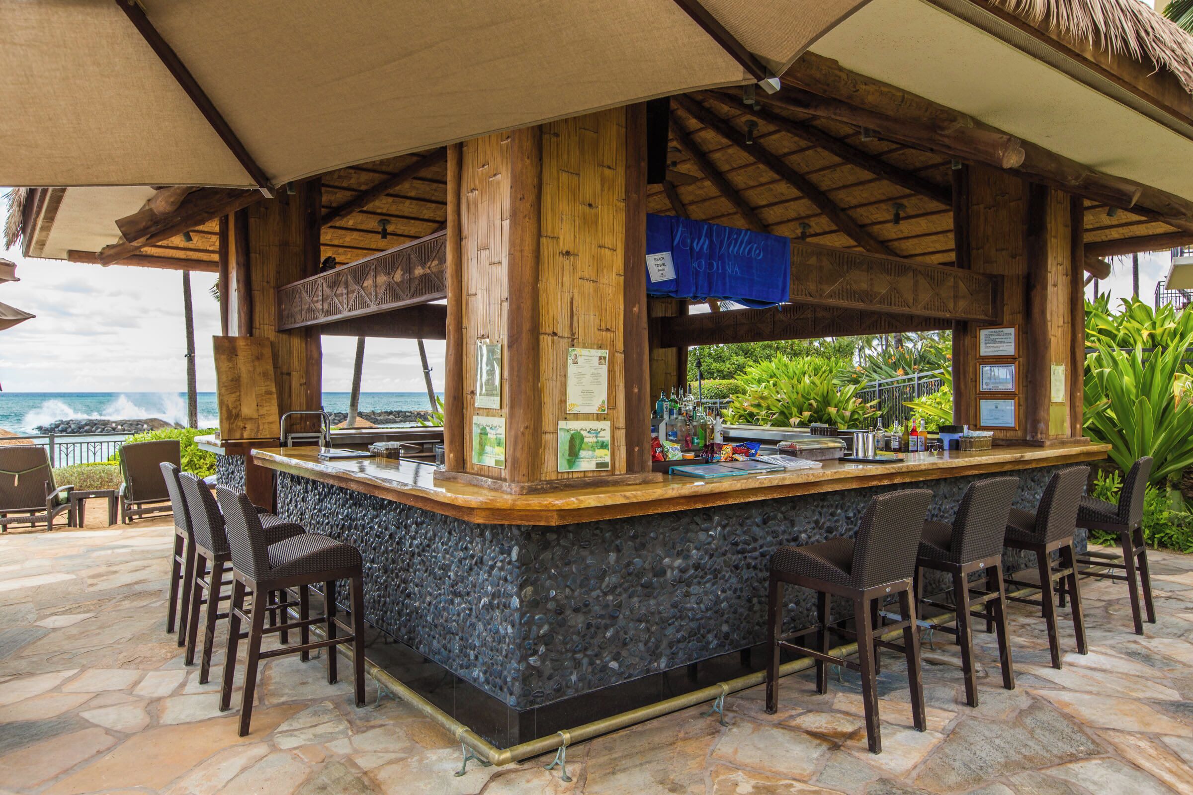 A bar area with a stone counter, wooden beams, and bar stools.