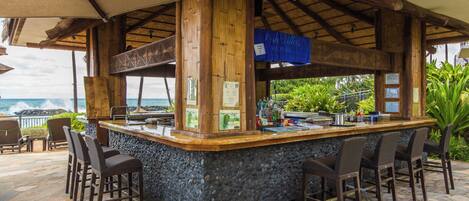 A bar area with a stone counter, wooden beams, and bar stools.