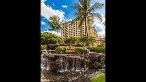 A hotel with a large building, a waterfall, and palm trees. - Hale Leilani Ko Olina Beachfront w/ Views! (Kapolei)
