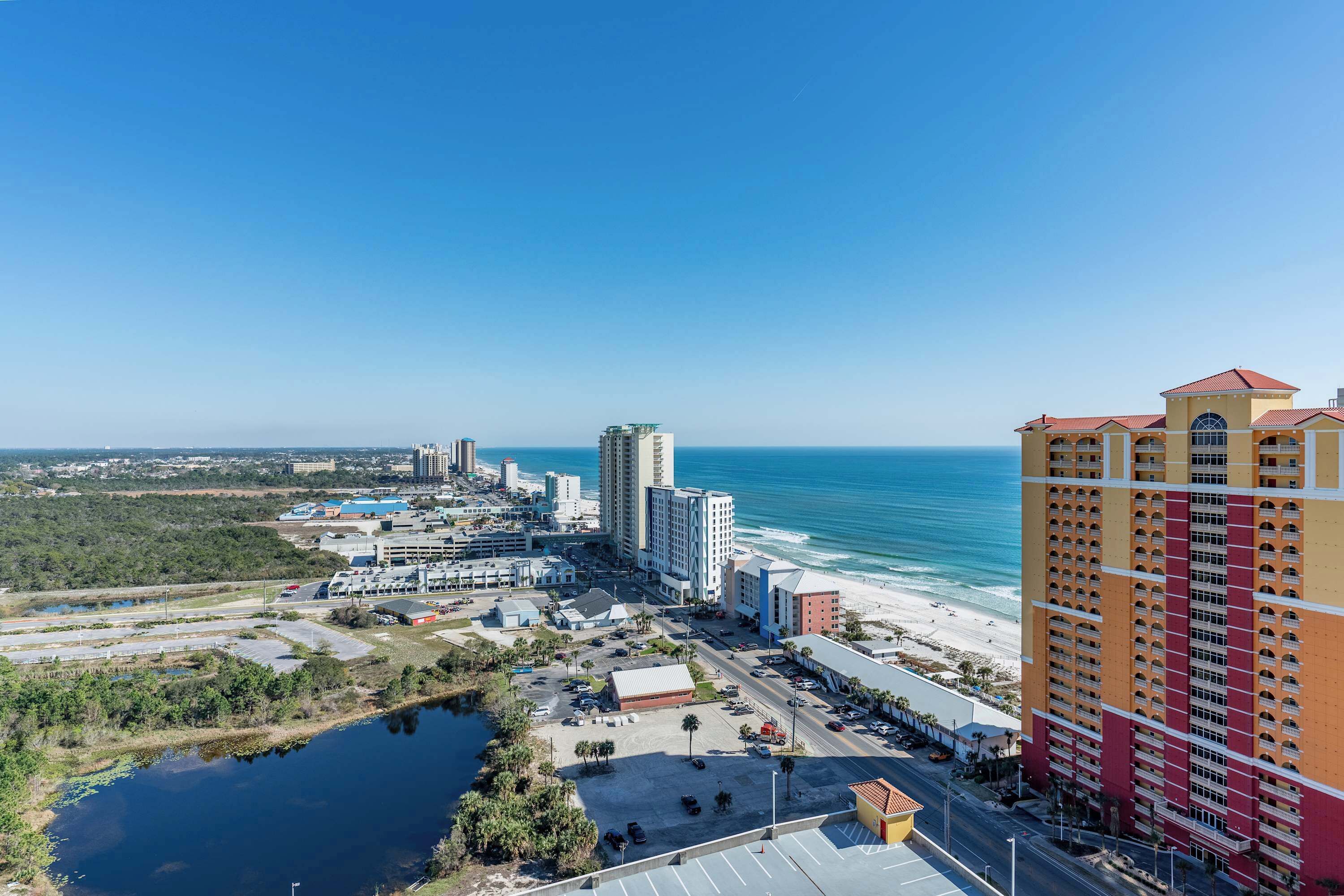 A coastal cityscape with high-rise buildings, a beach, and a marina.