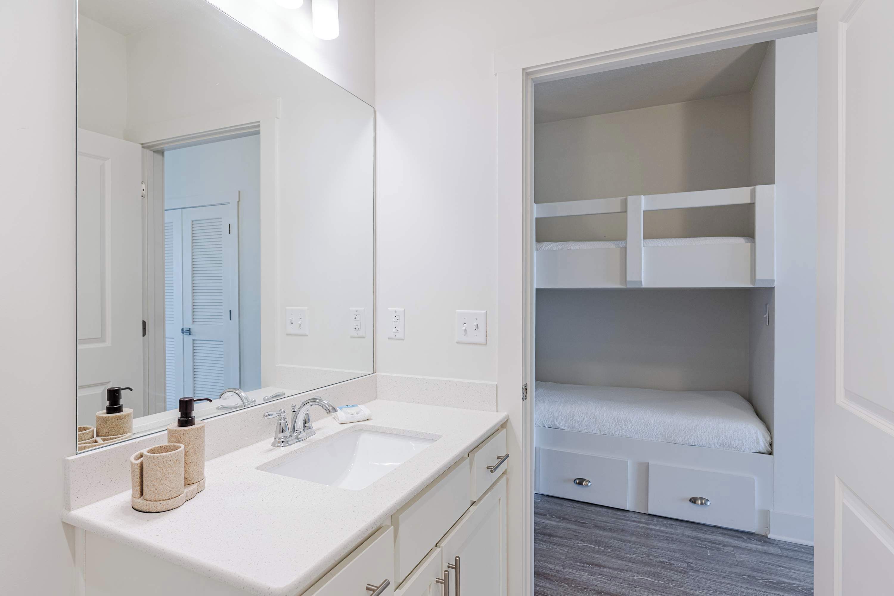 A modern bathroom with a double sink, a large mirror, and a walk-in closet with built-in shelves.