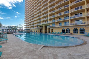 A hotel with a large pool, multiple balconies, and a Ferris wheel in the background.