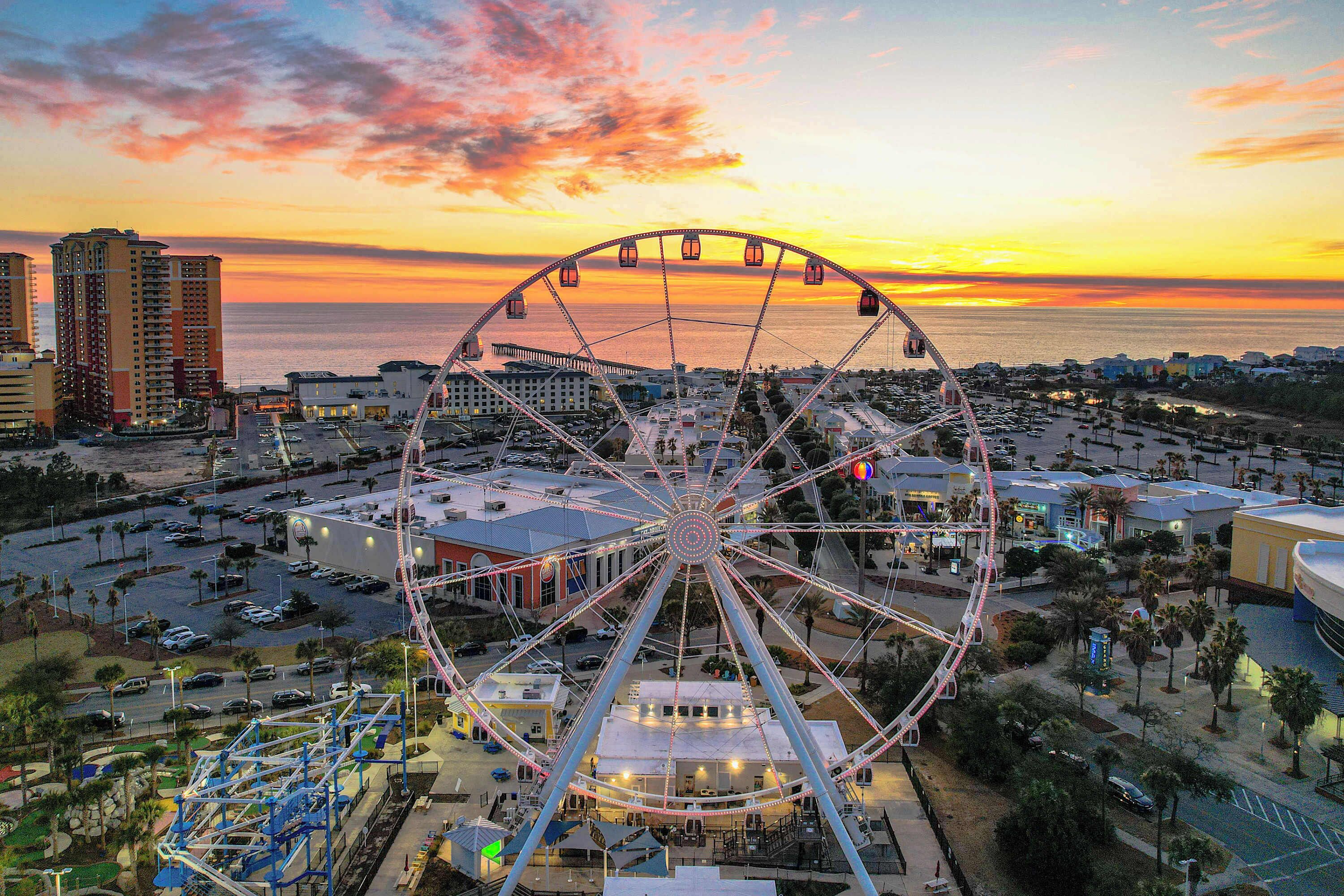 A large Ferris wheel with a view of the ocean and cityscape in the background.