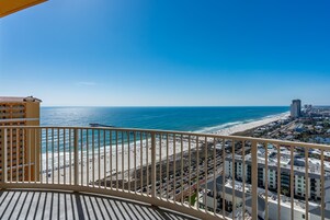 A balcony with a view of a beach and cityscape.
