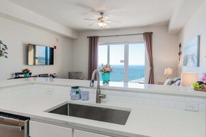 A modern kitchen with a large island, a built-in sink, and a ceiling fan.