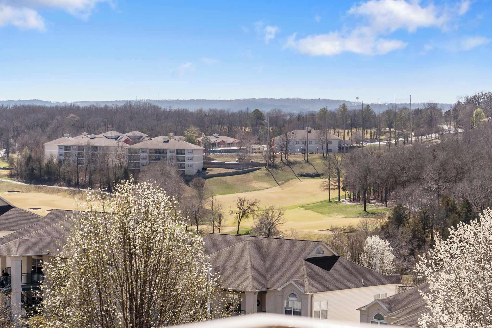 A residential area with apartment buildings, a golf course, and a hilly landscape.
