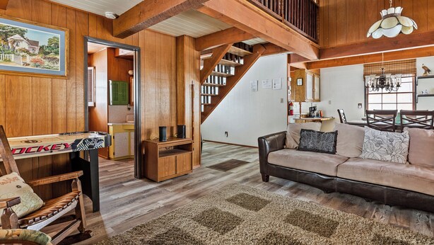 Ein geräumiges Wohnzimmer mit einer Holztreppe, einem Billardtisch und einem gemütlichen Sofa.
