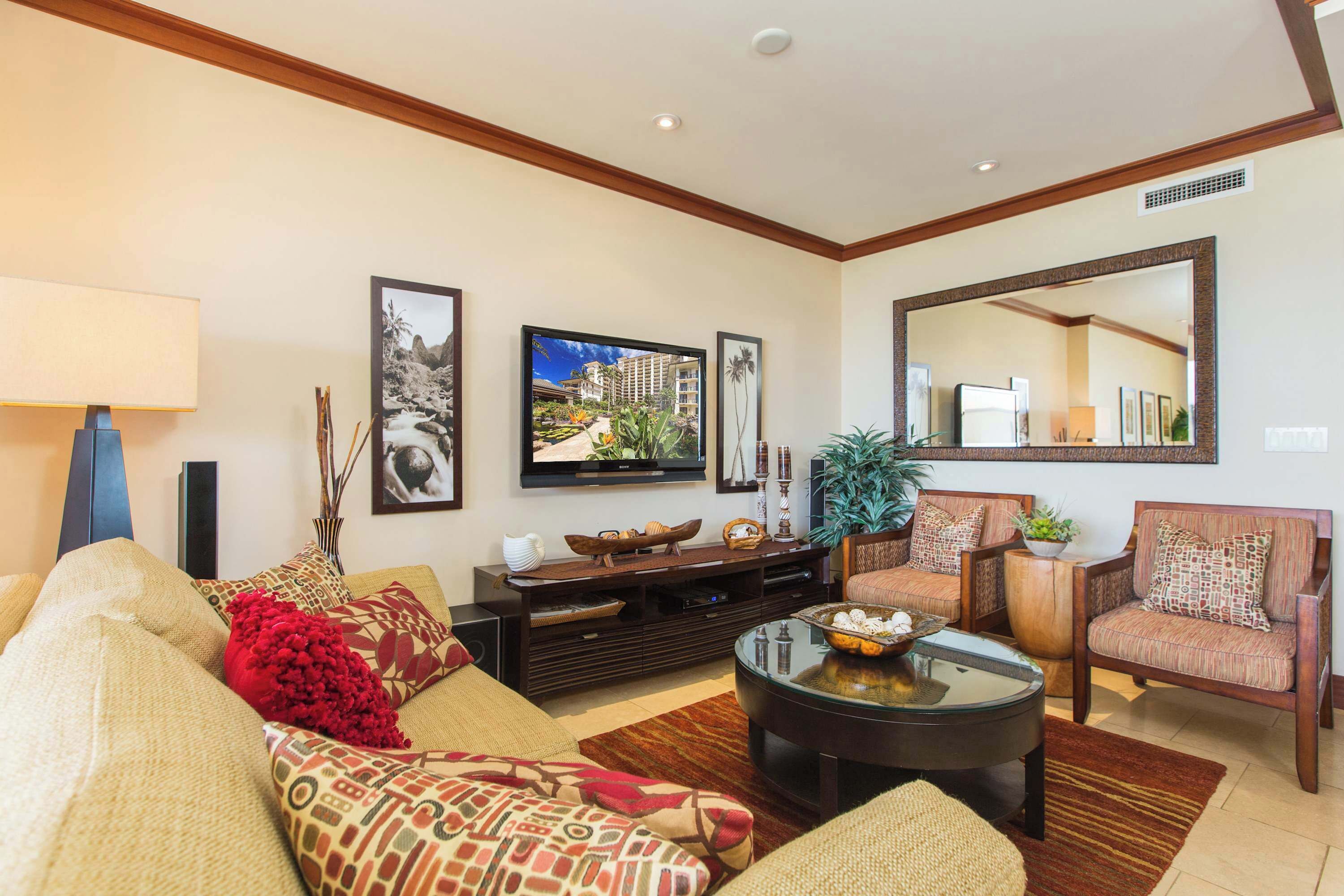 A living room with a sofa, armchairs, a coffee table, a TV, and framed pictures on the wall.