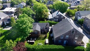 A residential area with houses, green lawns, and a body of water in the background. - Historic Nantucket Home | Hot Tub & Downtown Steps (Nantucket)