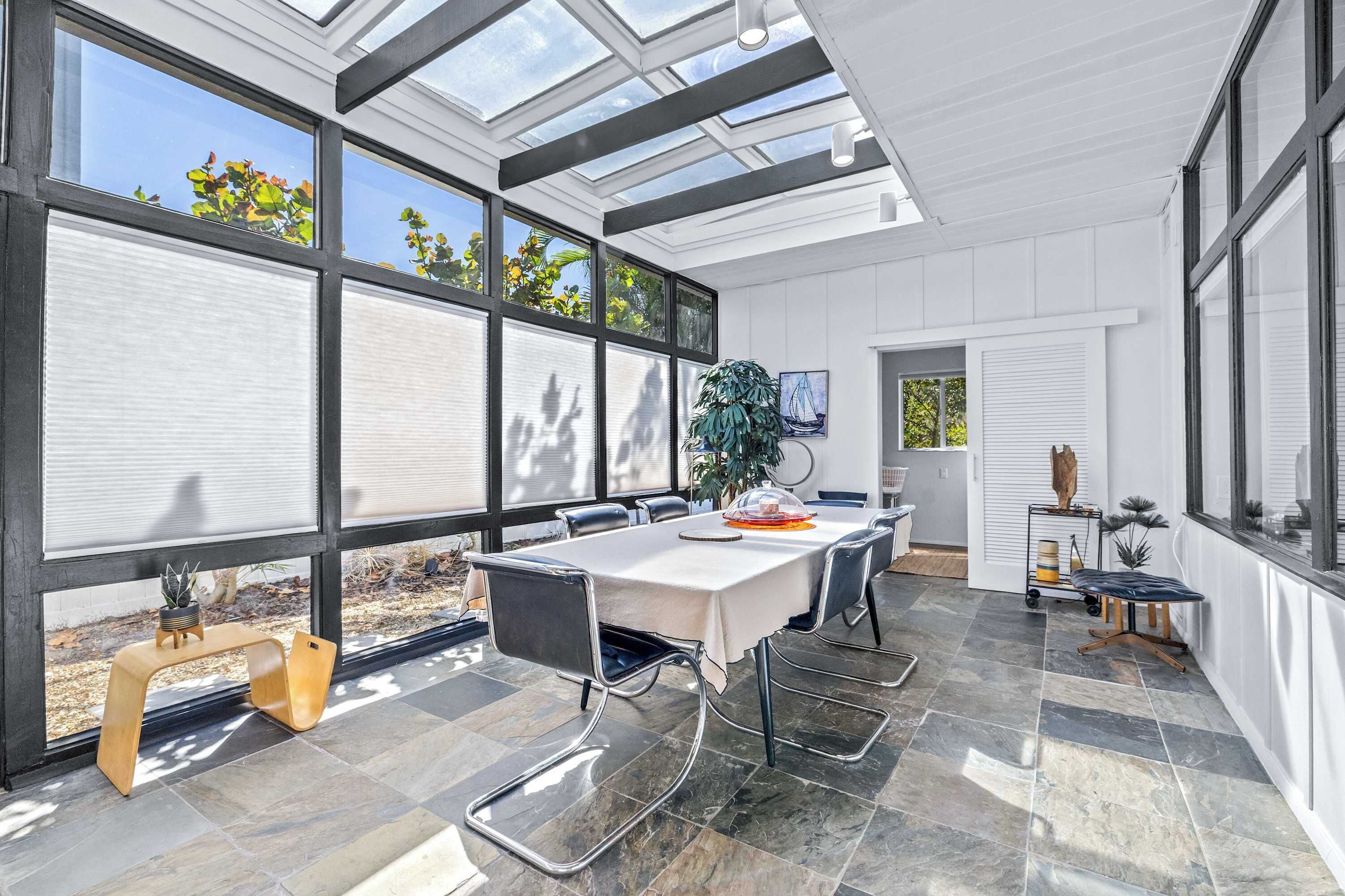 A modern kitchen with a large island, a dining table, and a view through the windows.
