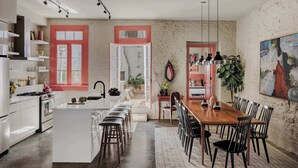Una cucina moderna con mobili bianchi, un'isola centrale e un'area pranzo con tavolo e sedie in legno.