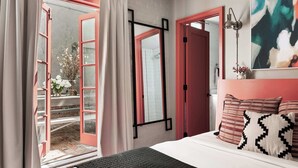 Una camera da letto con un letto, una finestra con tende, una porta e una lampada a muro.