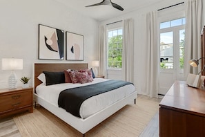Relax in this serene bedroom with a large bed, wooden nightstand, and bedside table, featuring two framed artworks above.