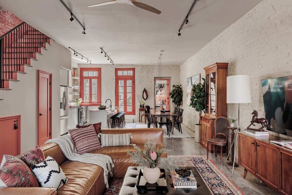 A spacious living area with a leather sofa, dining table, and a TV. - Luxury Historic Home Near to Downtown (New Orleans)