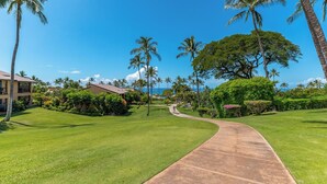 A well-maintained golf course with a curved pathway, surrounded by lush greenery and palm trees. - Gorgeous Expansive Condo in Wailea with HUGE Lanai & Ocean Views (Kihei)