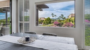A dining area with a table, chairs, and a view of a residential neighborhood with houses and greenery. - Gorgeous Expansive Condo in Wailea with HUGE Lanai & Ocean Views (Kihei)