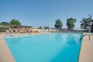 Piscina com espreguiçadeiras e área de estar coberta.