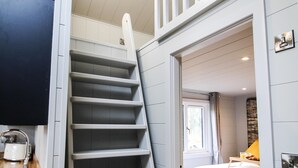 Un interior moderno con suelo de madera, una escalera que conduce a una zona superior y una cama con cabecero.