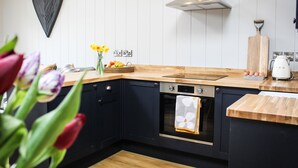 Una cocina con armarios oscuros, encimera de madera, un adorno con forma de corazón, un jarrón con flores y un tostador.