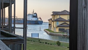 A waterfront view with a large cargo ship docked near a residential area.