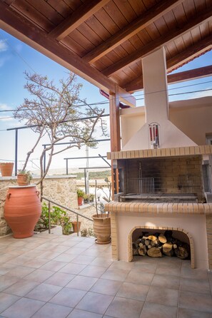 Un patio al aire libre con chimenea de ladrillo, macetas de terracota y un árbol.