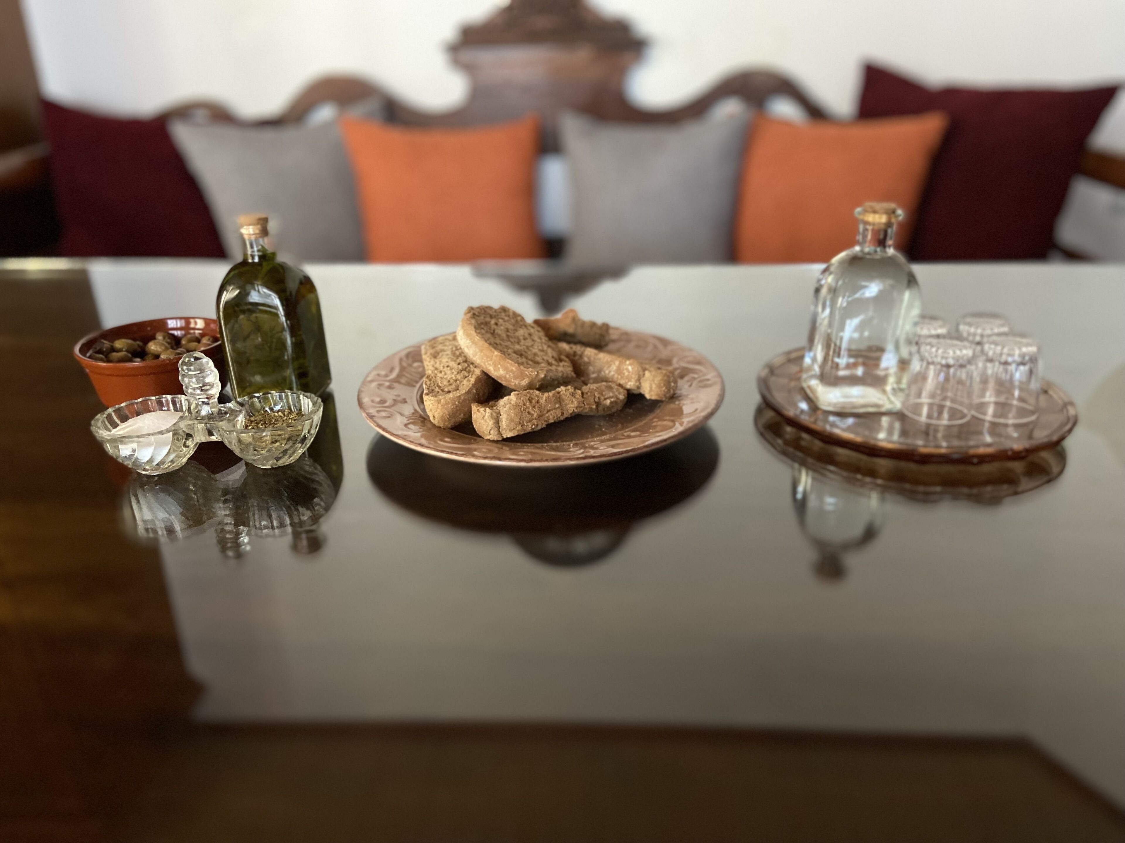 A table with a plate of cookies, a bottle, a glass bowl, and a set of glasses on a tray.