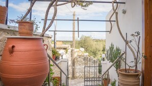 A staircase leading to a garden area with large terracotta pots and a metal gate. - Thòlos Home (Αρχοντική)