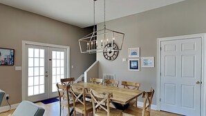 A dining area with a wooden table and chairs, a chandelier, and a staircase leading to another level. - Seahawk South C | Two Units In One, Community Pool + Steps to Beach (Fort Morgan)