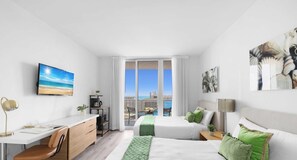A modern hotel room with a city view, a desk, a bed, and a coffee machine.