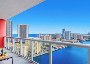 Een balkon met uitzicht op een stadsbeeld, een jachthaven en de oceaan.