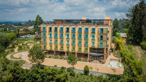 Um hotel com vários andares e telhado plano, rodeado por vegetação e um rio.