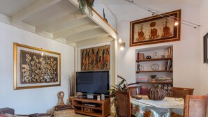 Een woonkamer met een televisie, boekenplanken en lijstwerken aan de wanden.