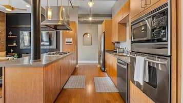 Une cuisine moderne avec des meubles en bois, des appareils électroménagers en acier inoxydable et un îlot central.