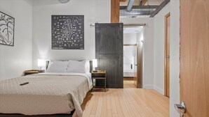 A bedroom with a bed, bedside tables, a map on the wall, and a door leading to another room. - Walk Anywhere Downtown Indy (Indianapolis)