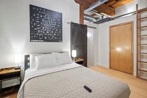 Ein Schlafzimmer mit einem Bett, einer an der Wand befindlichen Karte, einer Holzleiter und einer Tür.