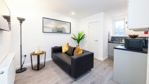 A modern living room with a black sofa, a small side table, and a potted plant.