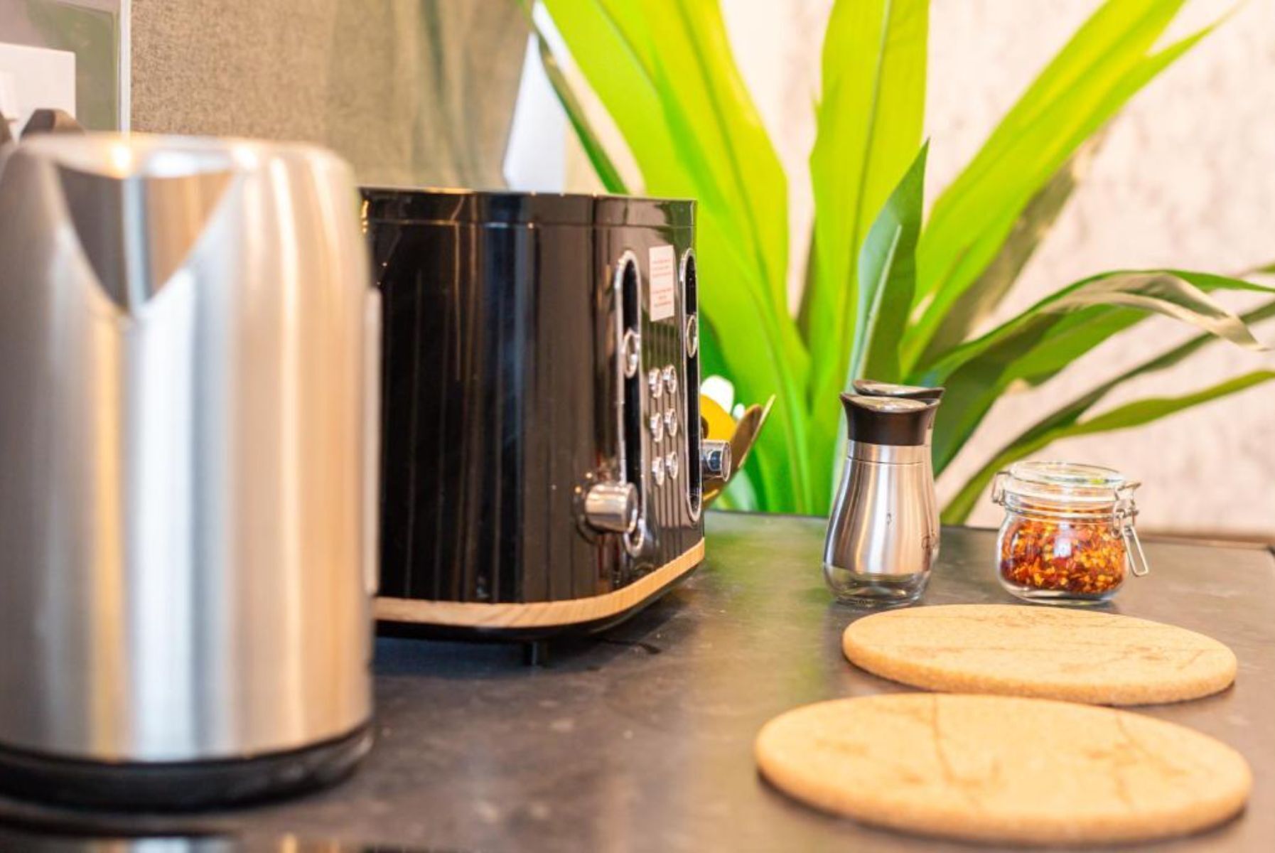 A kitchen counter with a coffee maker, a pepper grinder, and two cookies.