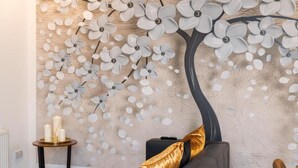 A modern living room with a large abstract wall art, a dark sofa with a gold throw pillow, a small round table with candles, and a black ottoman.