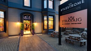 Exterior del hotel Kylestrome, con fachada de ladrillo, zona de estar al aire libre y un letrero para el restaurante The Strayaig.