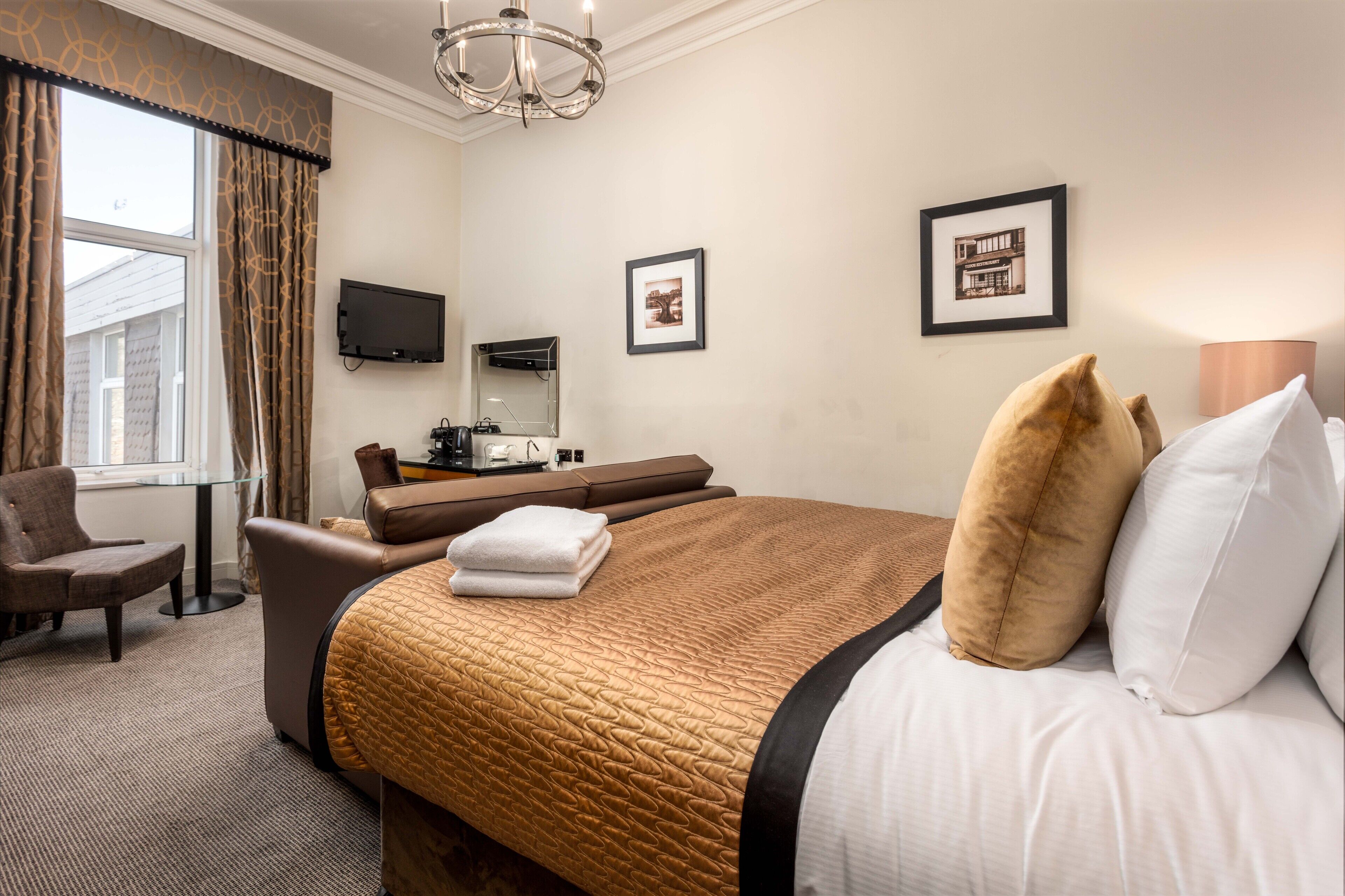 Une chambre d’hôtel avec un grand lit, un bureau avec un ordinateur, une chaise et un téléviseur fixé au mur.