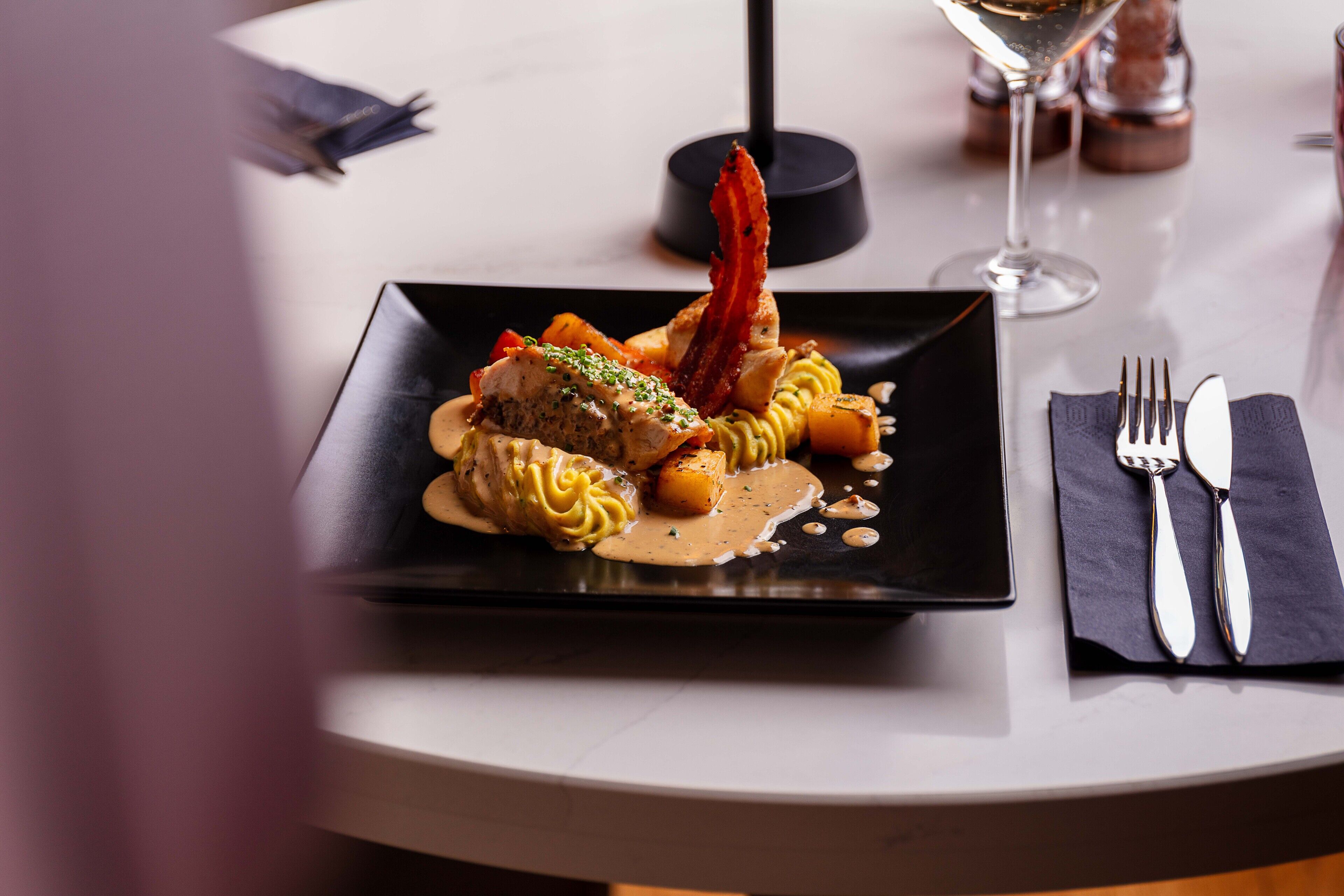 A dining table with a plate of food, a wine glass, and cutlery.