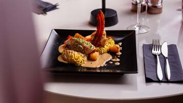 A dining table with a plate of food, a wine glass, and cutlery.
