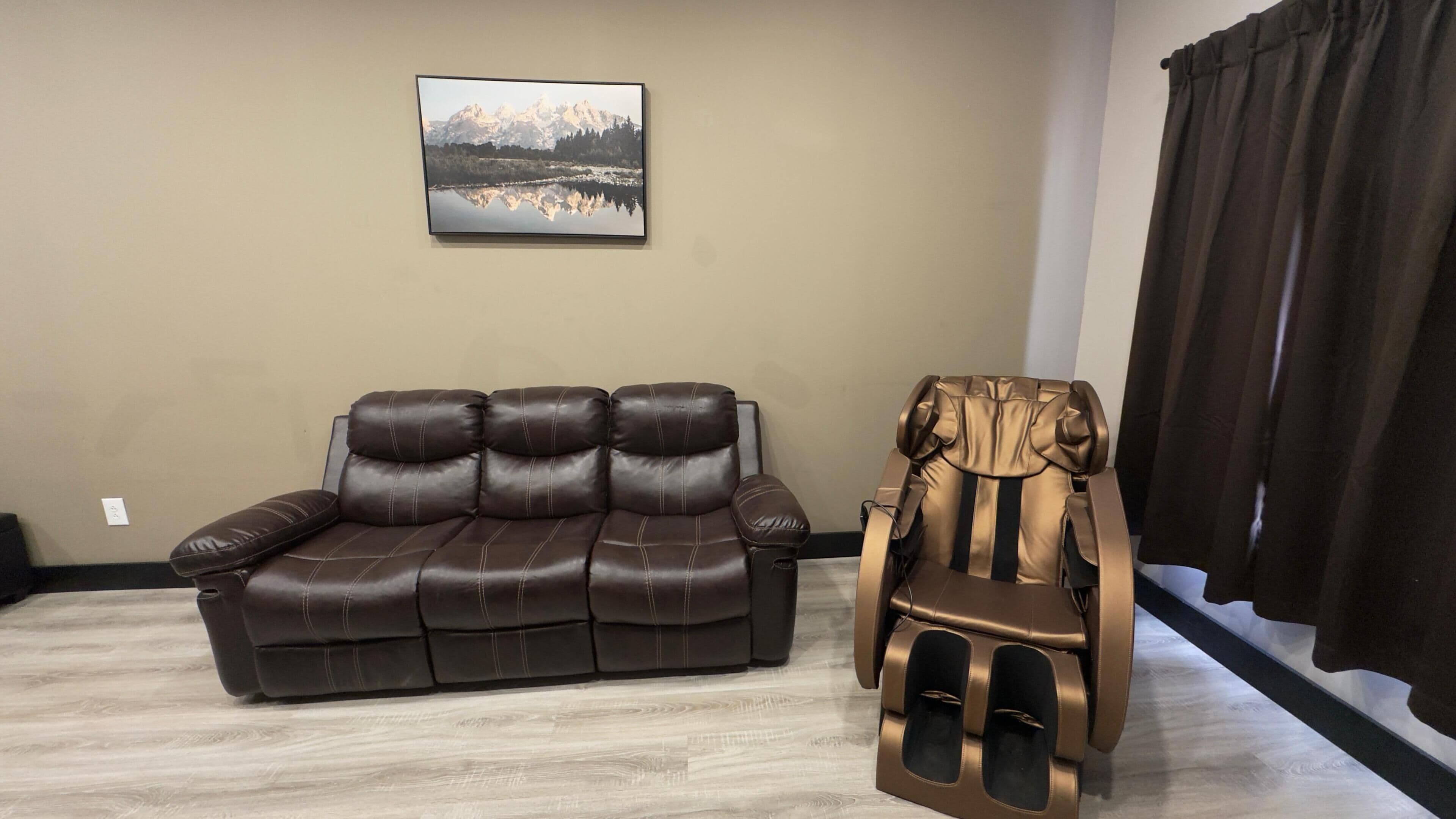 Una sala de estar con un sofá de cuero marrón y un sillón de masaje.