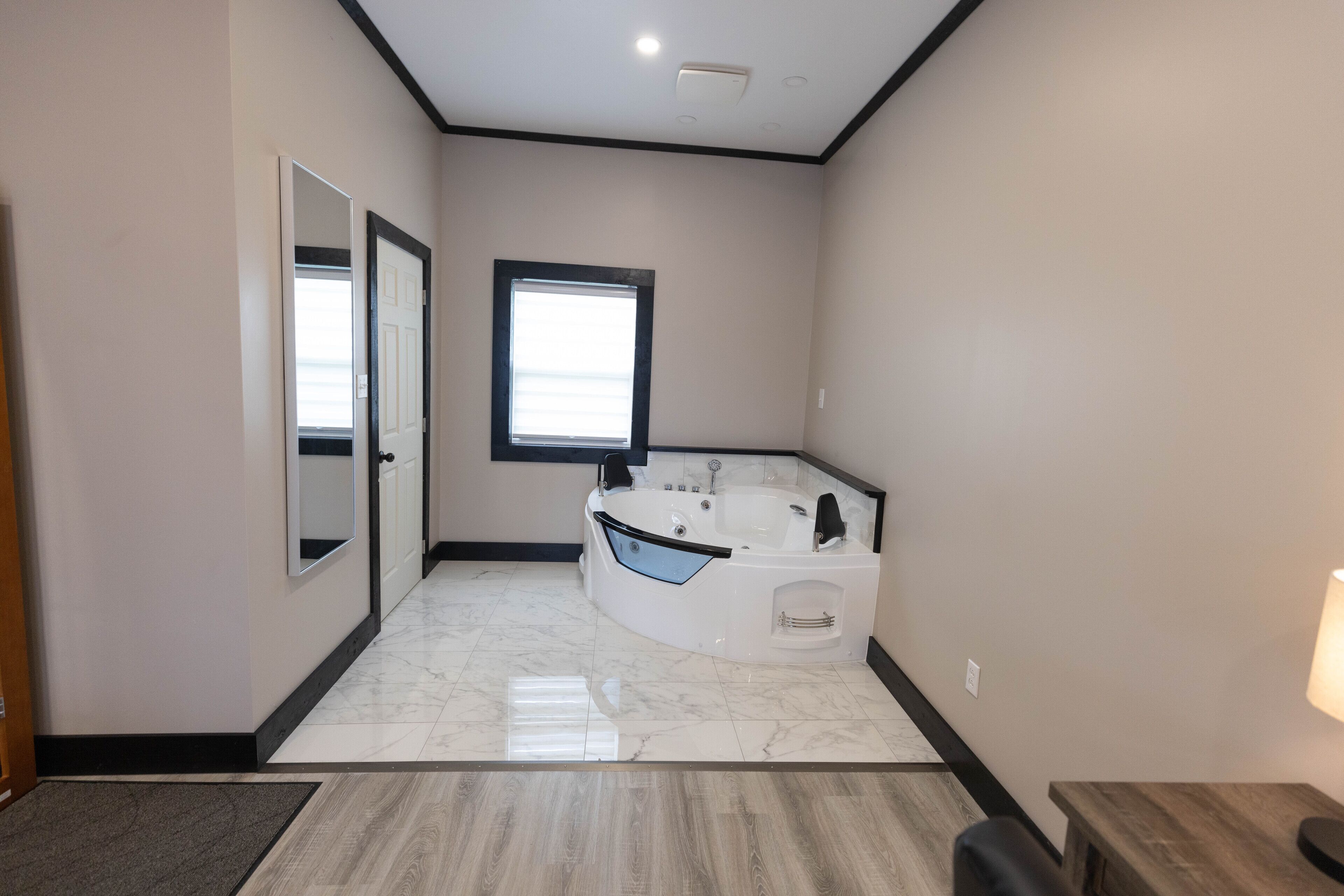 Un baño moderno con una bañera independiente, un espejo grande y una ventana que proporciona luz natural.
