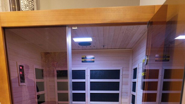A wooden elevator with a glass door, wooden paneling, and a small platform at the bottom.